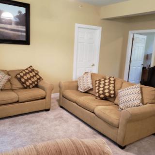 A cozy living room with beige couches and decorative pillows, complemented by a framed artwork on the wall.