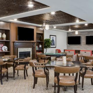 A modern dining area with wooden chairs and tables, featuring a fireplace and multiple television screens.
