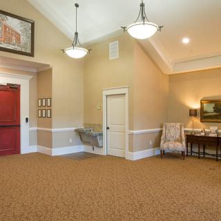 A warm and inviting lobby with elegant decor, featuring chandeliers, a red door, and comfortable furniture.