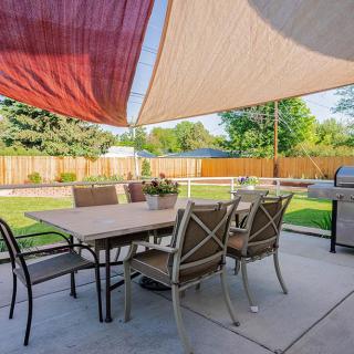 A cozy backyard patio with a dining set under shade sails, perfect for outdoor gatherings.