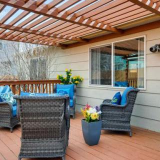 A cozy patio with wicker furniture and a pergola, featuring vibrant cushions and decorative plants.