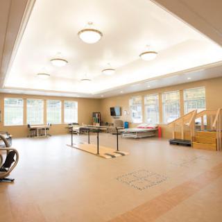 A spacious and well-lit rehabilitation room equipped with exercise equipment, ideal for therapy sessions.