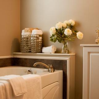 A luxurious bathroom with a tub, neatly folded towels, and a vase of white flowers.