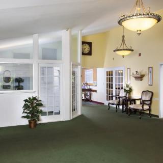 A bright, welcoming lobby area featuring chandeliers, green carpet, and comfortable furniture.