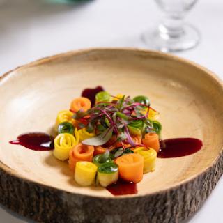 A beautifully plated dish featuring an array of colorful vegetables, drizzled with a rich sauce.