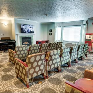 A cozy theater room with patterned armchairs, a piano, and a popcorn machine.