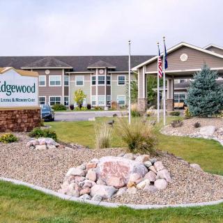 A well-maintained building entrance with a sign, surrounded by landscaped shrubs and gravel.