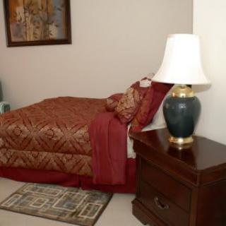 A cozy bedroom with a patterned bedspread, nightstand, and lamp.