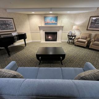 A cozy living room with a fireplace, sofa, and piano.