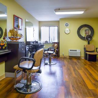 An interior view of a hair salon featuring chairs, mirrors, and wooden flooring.