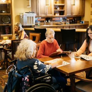 A group of seniors engaged in an art activity together in a cozy indoor setting.