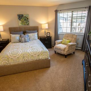 A cozy bedroom with modern decor, featuring a comfortable bed and a stylish armchair by the window.