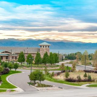A picturesque view of a modern building surrounded by lush greenery and mountains in the background.