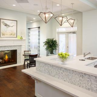 A modern kitchen with elegant lighting, a fireplace, and sleek countertops.
