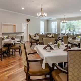 A well-organized dining area with neatly set tables and comfortable chairs under elegant chandeliers.