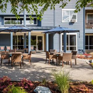 A well-maintained outdoor patio area with chairs and tables, surrounded by landscaping and a building in the background.