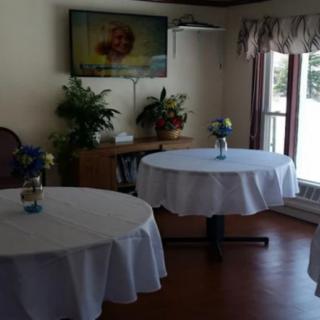 A cozy dining area with round tables, a television, and decorative plants.