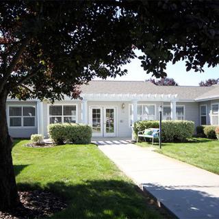 A suburban house with a well-kept lawn and a concrete pathway leading to the entrance.