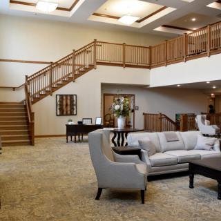 A modern and spacious lobby with elegant furniture and wooden stairs.