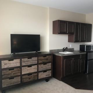 A modern kitchen with dark cabinets, a TV, and appliances.