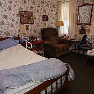 A cozy bedroom with a hospital bed, floral wallpaper, and comfortable furnishings.