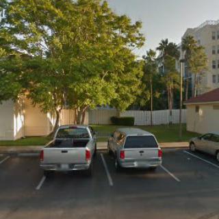 Two cars parked in a parking lot next to a building surrounded by trees.