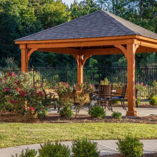 A wooden gazebo with seating, surrounded by a landscaped garden.