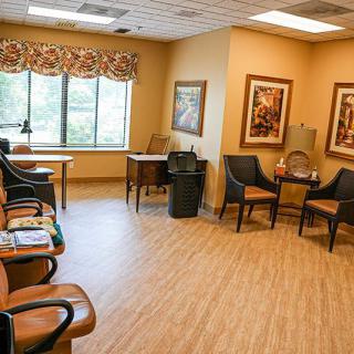 A cozy waiting room with comfortable seating, large windows, and artwork on the walls.
