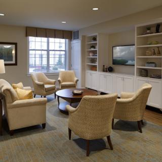 A cozy living room with comfortable seating, a round table, built-in shelves, and a television.