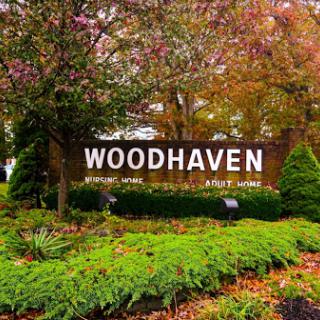 A welcoming sign for Woodhaven, surrounded by vibrant autumn foliage.