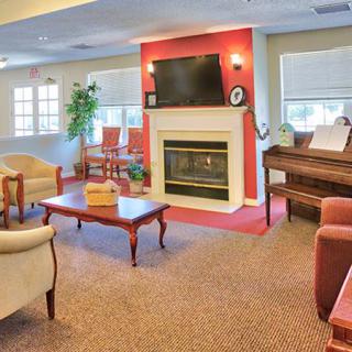 A cozy living room with a fireplace, television, piano, and comfortable seating.