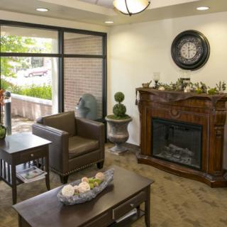 A cozy waiting room featuring a fireplace, armchair, and stylish decor.