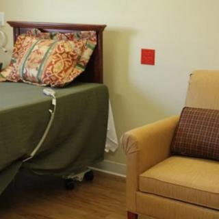 A cozy room with a bed and an armchair featuring decorative pillows.
