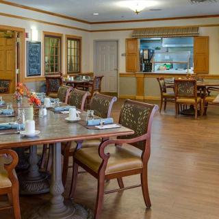 A spacious dining room with neatly arranged tables and chairs, featuring warm wooden furniture and a cozy ambiance.