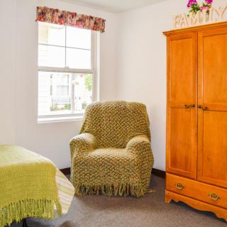 A cozy bedroom with an armchair and wooden wardrobe.