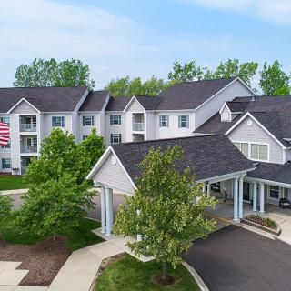 A residential building with a welcoming entryway, surrounded by trees and displaying a flag.