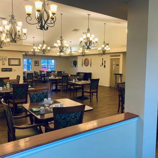 A cozy dining area with elegant chandeliers and neatly arranged tables.