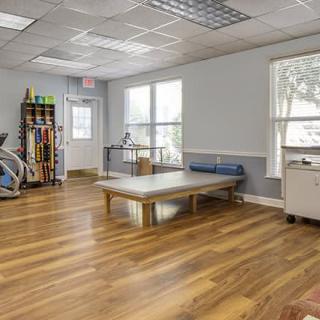 A spacious therapy room with exercise equipment and natural lighting.