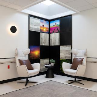 A modern lounge area featuring two stylish chairs, a small table, and vibrant wall art.