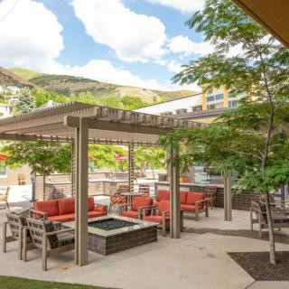 A scenic outdoor patio with a pergola, surrounded by trees and mountains.