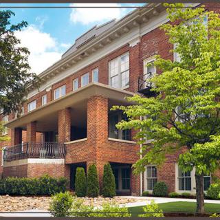 A residential building with brick facade surrounded by greenery.