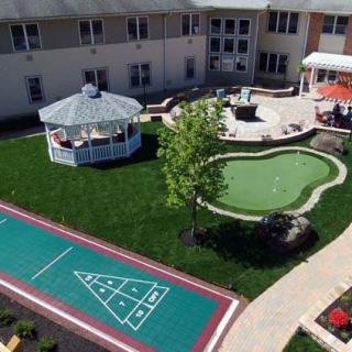 An outdoor recreational area featuring a gazebo, shuffleboard court, mini-golf course, and patio.