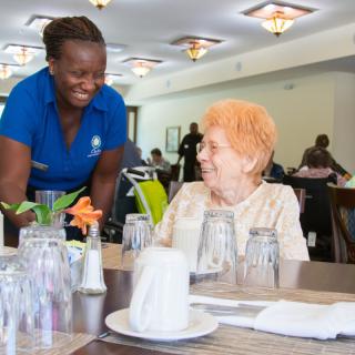 A staff member provides friendly service to a seated customer in a restaurant setting.