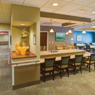 Modern lounge area with a long table and chairs, featuring stylish decor and warm lighting.