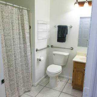 A clean and tidy bathroom featuring a toilet, sink, and shower with a patterned curtain.