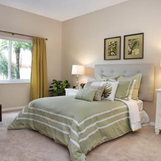 A cozy bedroom with green bedding and soft lighting.