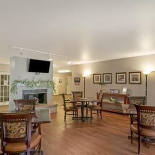A cozy living space with seating and dining areas, featuring a fireplace and wall-mounted television.