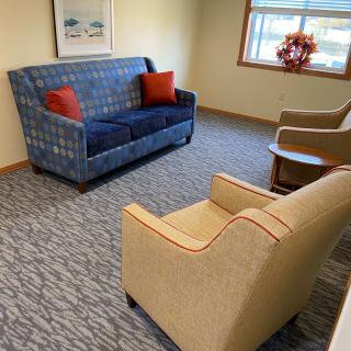 A cozy living room setting with a blue sofa, red cushions, and two beige armchairs.