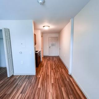 A spacious and modern apartment hallway with wooden flooring and light-colored walls.