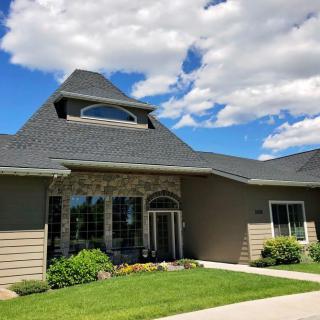 A modern house with a unique roof design under a partly cloudy sky.